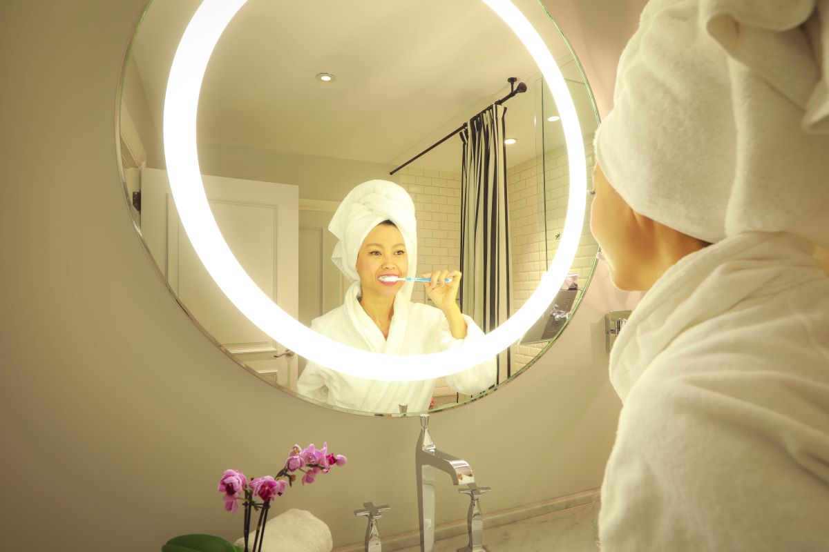 mujer cepillando sus dientes frente a un espejo en tendencia led para baño