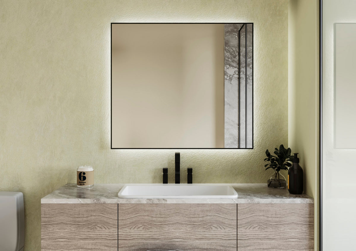 Espejo ALUMINIUM cuadrado con marco negro y halo de luz sobre un mueble de lavabo de madera