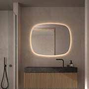 Espejo de forma orgánica Braga retroiluminado sobre un mueble de baño
