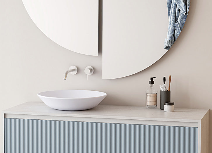 Espejo de baño sin luz CUTTA SIN de forma orgánica, dos semicírculos independientes sobre un mueble de lavabo azul con lavabo de sobre encimera