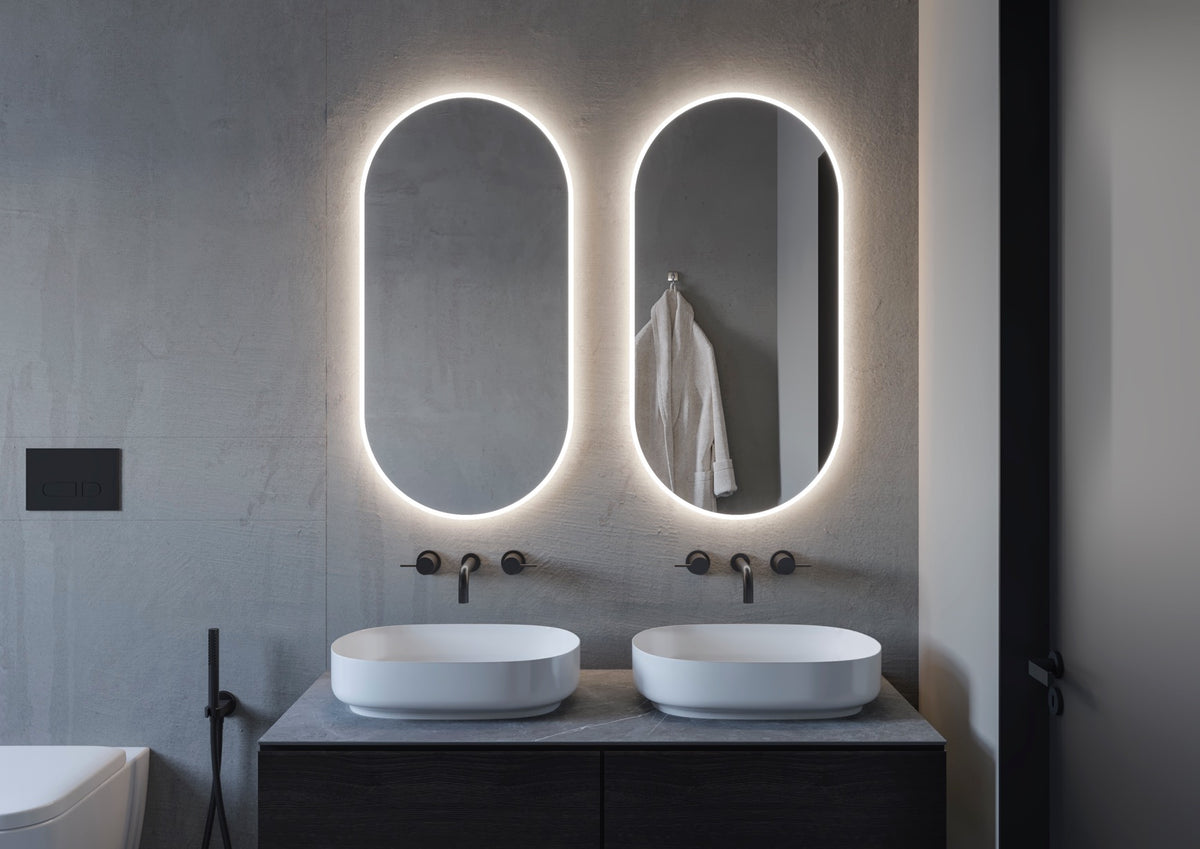 Espejo ovalado Denor a medida con luz frontal y retroiluminado sobre lavabo doble