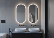Espejo ovalado Denor a medida con luz frontal y retroiluminado sobre lavabo doble
