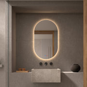 Espejo ovalado retroiluminado Segovia sobre un lavabo de piedra
